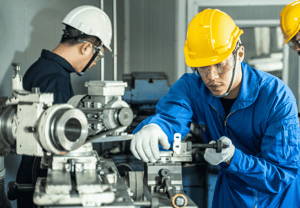 Group of factory workers using machine equipment in factory workshop